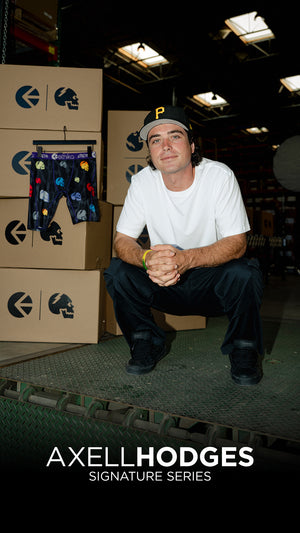 Man sitting in a warehouse with boxes and a display of underwear, featuring 'Axell Hodges Signature Series'.