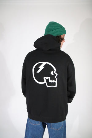 Axell Hodges wearing a black hoodie with a white slayco skull logo on the back, standing against a plain background.