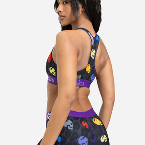 Woman wearing a sports bra and shorts with colorful designs on a white background
