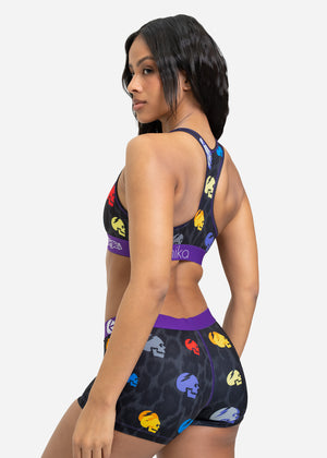 Woman wearing a sports bra and shorts with colorful designs on a white background